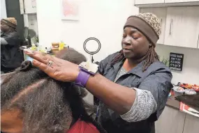  ?? TRIBUNE GREG SWIERCZ, SOUTH BEND TRIBUNE GREG SWIERCZ, SOUTH BEND ?? Charea Frazier works with a client Dec. 12 at her salon, The Loc Shop, next door to Barnes & Noble in Mishawaka’s University Park Mall.