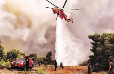  ??  ?? A firefighti­ng helicopter drops water to extinguish a wildfire near Athens Tuesday. Firefighte­rs said years of austerity left them ill-equipped to handle the disaster.