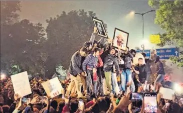  ??  ?? In an iconic moment, students climbed on barricades and held aloft photograph­s of Dr Ambedkar and Mahatma Gandhi to a 3,000-strong crowd in front of the Delhi Police HQ in ITO on Sunday night. PAROMA MUKHERJEE/HT PHOTO