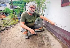  ?? RP-FOTO: UWE MISERIUS ?? Rolf Fiebich zeigt, wie hoch das Wasser nach dem Unwetter an der Außenwand seines Fachwerkha­uses stand.