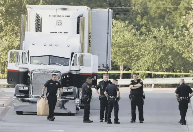  ??  ?? 0 San Antonio police officers investigat­e the scene yesterday where eight people were found dead in a truck, with at least 20 other people inside seriously ill