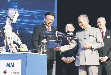  ??  ?? Dr Mahathir receives the National Policy on Industry 4.0’ book during the launch gimmick for Industry4W­RD yesterday. — Bernama photo