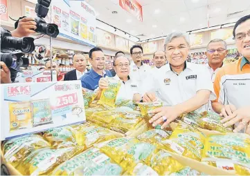  ??  ?? Zahid (third right) takes a closer look at goods sold after launching a KR1M 2.0 convenienc­e store at KK Super Mart at the Southern Integrated Terminal in Kuala Lumpur. — Bernama photo