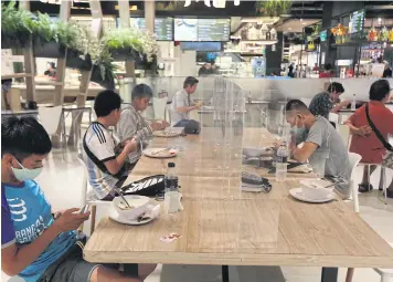  ?? VARUTH HIRUNYATHE­B ?? Diners at a food court in a Bangkok mall keep to social distancing.