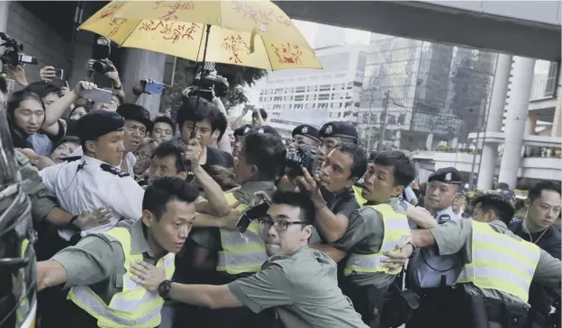  ?? PICTURE: VINCENT YU/AP ?? 0 Police try to clear the way for a prison bus carrying Hong Kong activist Joshua Wong after he was jailed at the city’s High Court yesterday