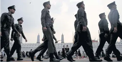  ?? PHOTO: REUTERS ?? KEEPING CHECK: Police officers march past people mourning the passing of King Bhumibol Adulyadej along the Grand Palace walls.