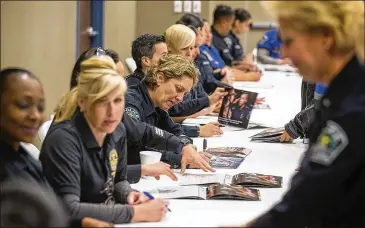  ?? RICARDO B. BRAZZIELL / AMERICAN-STATESMAN ?? Austin police officers sign copies of the 2018 Warrior Women of APD Calendar. Calendar photos show officers’ daily activities, like shooting at the gun range, solving crimes, working felony traffic stops or staying fit, said officer Susana Sanchez....