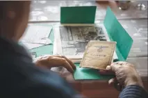  ?? GORDON WELTERS / THE NEW YORK TIMES ?? Günter Debski , who was at Seelow Heights, the biggest World War II battle on German soil, examines mementos including his Wehrmacht payroll book, earlier this month at his home in Eisenhütte­nstadt, Germany. Debski, who still has a piece of shrapnel...