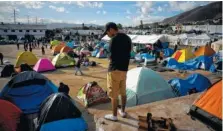  ?? AP PHOTO/RAMON ESPINOSA ?? A migrant does a crossword puzzle at the new shelter where he and others were transferre­d Sunday after the sanitary conditions worsened at a previous shelter in Tijuana, Mexico.