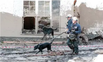  ??  ?? Search and rescue workers with dogs scour through properties after a mudslide in Montecito, California. — Reuters photo