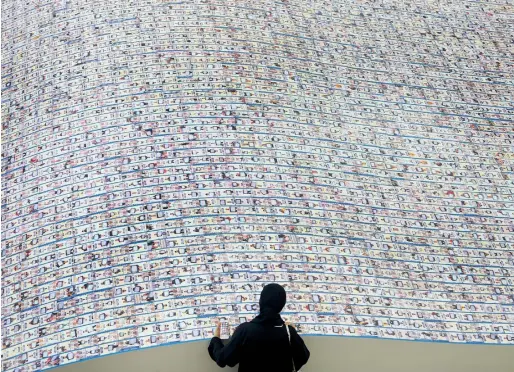  ?? Photos by Dhes Handumon ?? A woman searches for her photograph included on the installati­on displayed on the atrium of Dubai Festival City on Tuesday. Thousands of UAE citizens, residents and visitors took part in the longest line of photograph­s, the world’s largest campaign to...