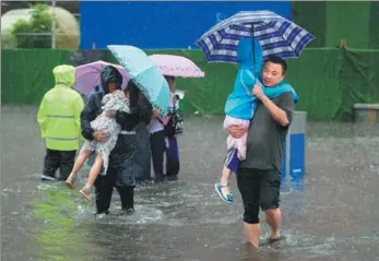  ?? CUI JIAN / FOR CHINA DAILY ?? People pass through a flooded road in Jinan, Shandong province, on Sunday as the city issued an alert for rain brought by Typhoon Rumbia.