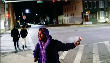  ?? AP PHOTO BY PATRICK SEMANSKY ?? Erricka Bridgeford spreads sage on Dec. 14 as she performs a ceremony near the scene of a homicide in Baltimore. Bridgeford leads near-daily ceremonies in an effort to transform murder sites into places of inspiratio­n. Bridgeford is a profession­al...