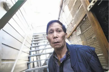  ?? Photos by Lea Suzuki / The Chronicle ?? Above: Huang Wong shows an exterior stairwell landing at 1350 Stockton where he says tenants used to hang clothes to dry, now forbidden under the new rules. Below: Clothes hang in a window at the building, a complex of 80-square-foot single rooms.