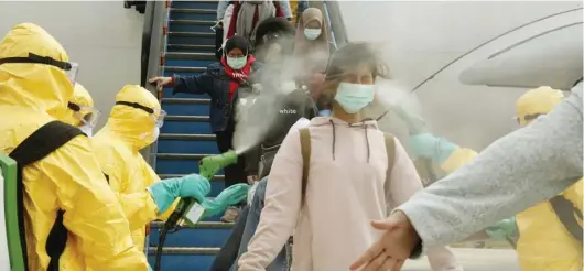  ?? INDONESIAN FOREIGN MINISTRY VIA AP ?? MENUJU KARANTINA: WNI yang dievakuasi dari Wuhan disemprot cairan disinfekta­n saat turun dari pesawat di Bandara Hang Nadim, Batam, kemarin (2/2).