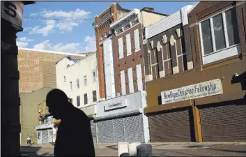  ?? Patrick Semansky The Associated Press ?? A man walks past vacant storefront­s Tuesday at the Old Town Mall in Baltimore. New research suggests that impoverish­ed Americans are getting left out even when their communitie­s enjoy hiring booms.