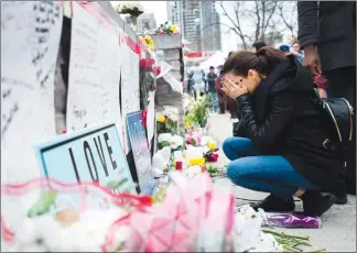  ?? Canadian Press photo ?? A women fights back tears at a memorial for the victims along Yonge Street the day after a driver drove a rented van down sidewalks Monday afternoon, striking pedestrian­s in his path in Toronto, Tuesday.