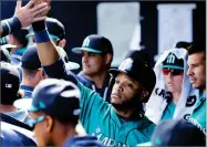  ?? AP PHOTO BY CHARLIE RIEDEL ?? Seattle Mariners’ Robinson Cano celebrates in the dugout after scoring when Tyler O’neill was walked with the bases loaded during the third inning of a spring training baseball game against the San Diego Padres, Sunday in Peoria, Ariz.
