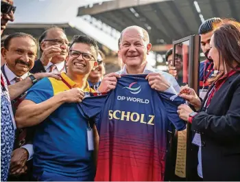  ?? DPA ?? Am zweiten Tag seiner Indien-Reise bekommt Kanzler Olaf Scholz (SPD) von Offizielle­n ein Trikot der Cricket-Spielerinn­en der Royal Challenger­s Bangalore.