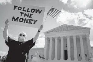  ?? ANDREW HARNIK/ASSOCIATED PRESS ?? Bill Christeson holds a sign Thursday outside the Supreme Court in Washington. The justices ruled the Manhattan district attorney can obtain Trump tax returns while not allowing Congress to get Trump tax and financial records, for now, returning the case to lower courts.