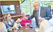  ??  ?? Britain's Prime Minister and leader of Conservati­ve Party, Boris Johnson, pets a customer's dog in the beer garden during a visit to The Mount Tavern pub and restaurant in Wolverhamp­ton, central England, on Monday.