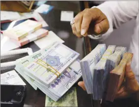  ??  ?? A man counts Lebanese pounds at a currency exchange shop in Beirut. Lebanon’s talks with the IMF stalled this year over a row among Lebanese government officials, bankers and political parties over vast financial losses.