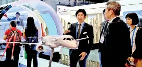  ??  ?? Exhibitors standing next to the Spacejet model display at the Mitsubishi Aircraft Corporatio­n booth during the Singapore Airshow in Singapore