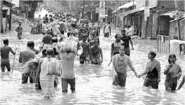  ?? — AFP photo ?? Indian residents wade through flood waters in Balurghat in West Bengal. At least 221 people have died and more than 1.5 million have been displaced by monsoon flooding across India, Nepal and Bangladesh officials said Aug 15, as rescuers scoured...