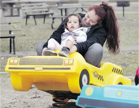  ?? NICK BRANCACCIO ?? Kelsey Holland takes her two-year-old daughter Adrieonna Dodge-Hollard for a spin on a playground ride on Matchette Road near Malden Park on Wednesday, when Windsor temperatur­es soared to a record high of 16.5 C. The warm weather will continue for at...