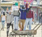  ?? AP FILE ?? Protesters hold stones and placards during a demonstrat­ion in Kashmir. A series of viral videos showing alleged human rights excesses have ratcheted up the temperatur­e in the Valley.