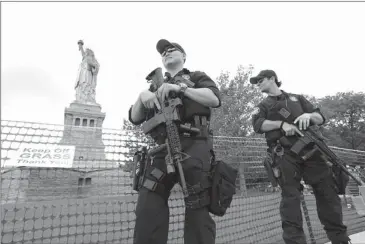  ??  ?? United States Park Police SWAT team members stand guard Thursday at the Statue of Liberty in New York. The Statue of Liberty finally reopened on the Fourth of July months after Superstorm Sandy swamped its little island in New York Harbor as Americans...