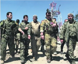  ?? Rodi Said / Reuters ?? A US military commander, second from right, with Kurdish fighters from the People’s Protection Units at their headquarte­rs, which were hit by Turkish air strikes in Syria yesterday.