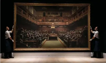  ?? Photograph: Simon Dawson/Reuters ?? Sotheby’s staff hold Banksy’s Devolved Parliament.