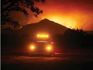  ?? Nhat V. Meyer/San Jose Mercury News via AP ?? Flames rise from a hillside Tuesday east of Santa Rosa, Calif. Wildfires whipped by powerful winds are sweeping through Northern California, sending residents on a headlong flight to safety through smoke and flames as homes burn. The death toll climbed...
