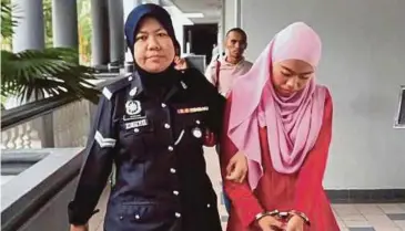  ?? PIC BY MUHAMMAD ZUHAIRI ZUBER ?? Nurul Aqilah Abdullah being led to the Ayer Keroh magistrate’s court.