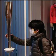  ?? (AP Photo/Jae C. Hong) ?? A boy with a mask poses with an Olympic torch while visiting Tokyo Olympic Museum. The coronaviru­s, which began in China two months ago, has infected more than 80,000 people globally and could affect this year’s Olympics.