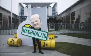  ?? (AP/Markus Schreiber) ?? An activist wearing a mask of German Chancellor Olaf Scholz holds a banner Tuesday reading “Sustainabl­e” during a protest against German climate policy in front of the chancellor’s office in
Berlin.