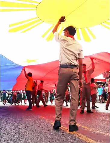  ?? PhotograPh by JoNaS rEyES for thE daily tribuNE ?? MEMbErS of the boy Scouts of the Philippine­s hoist a giant Philippine flag during the olongapo City fiesta Parade on friday.