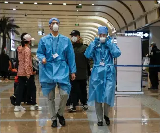  ??  ?? Workers wear protective clothing as they inspect equipment at a temperatur­e checking station at Beijing Airport