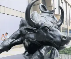  ?? REUTERS ?? People walk past a statue of bull in front of an investment company at a financial district in Beijing. Chinese stocks rose strongly for a second day yesterday, buoyed by a barrage of government support measures.