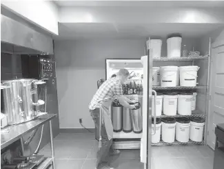  ??  ?? Wallner pulls a keg of beer from a refrigerat­or in his home brewery room.