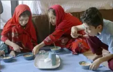  ?? Giovanna Dell’Orto/Associated Press ?? The three oldest Sultani children, from left, Sana, 8, Elaha, 9, and Shafiullah, 11, eat a midday meal made by their mother in the motel room the family shares in El Paso, Texas.