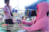  ??  ?? MARIA (kanan) membungkus sigup yang dibeli oleh pelanggann­ya.