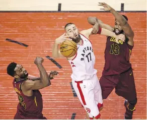  ??  ?? Jonas Valanciuna­s, middle, and the Toronto Raptors fought hard but still lost in overtime Tuesday in Game 1 against the Cleveland Cavaliers.