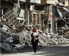  ?? — Reuters ?? In ruins: A man walking along a damaged street in Deir Ezzor, where tens of thousands of civilians have been trapped under IS siege for over two years.