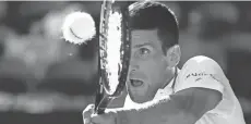  ?? RICK RYCROFT/AP ?? Novak Djokovic makes a backhand return to Frances Tiafoe during their second-round Australian Open match Wednesday in Melbourne.