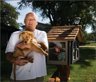  ?? (AP/Lincoln Journal Star/Eakin Howard) ?? Joe Knopp poses for a portrait with his 10-week-old golden retriever Gabby on Sunday on Everett Street in Lincoln, Neb.