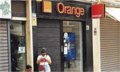  ?? Jon Nazca / Reuters ?? Una pareja delante de una tienda de Orange en Málaga.