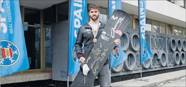  ??  ?? Lucas Eguibar posa para AS ayer en Madrid con su medalla de oro de campeón del mundo colgada al cuello y la tabla que usa en las competicio­nes de snowboard cross.