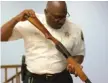  ?? MATTHEW HENDRICKSO­N/ SUN- TIMES ?? Dolton Police Chief Robert Collins Jr. examines a shotgun brought in at a gun buy- back event on Saturday.